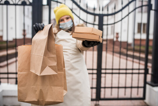 Portrait of beautiful woman delivery worker in medical mask walking the street. Food delivery concept.Helping volunteers for the disabled and the elderly. The first job of a teenager