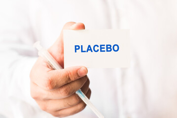 Word placebo on a white background with a syringe in hand. Preventive Medicine