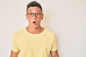 Young hispanic boy wearing casual clothes and glasses scared and amazed with open mouth for surprise, disbelief face