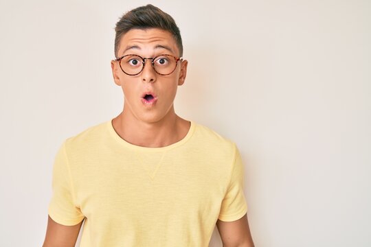 Young hispanic boy wearing casual clothes and glasses scared and amazed with open mouth for surprise, disbelief face