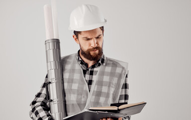 A builder in a helmet with a tube in his hands a blueprint on a light background paper