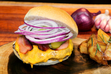 Hamburger. Made on the barbecue grill. With cheese, bacon, onion, pickle. On wooden background