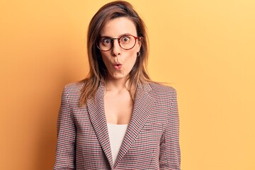 Young beautiful woman wearing business clothes and glasses scared and amazed with open mouth for surprise, disbelief face