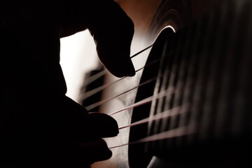Un close-up de una mano tocando una guitarra con cuerdas de nylon