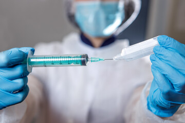 A medical worker types medicine into a syringe . Ampoule and syringe close-up. The concept of vaccination against coronavirus.