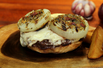 Hamburger. Made on the barbecue grill. With cheese, bacon, onion, pickle. On wooden background