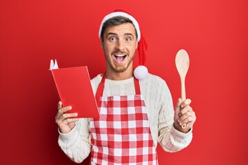 Handsome caucasian man cooking wearing baker apron and christmas hat celebrating crazy and amazed...