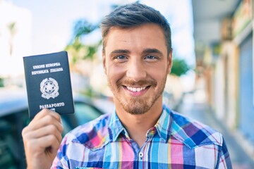 Young caucasian tourist man smiling happy holding italian passport walking at the city.