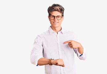 Young handsome man wearing business clothes and glasses in hurry pointing to watch time,...