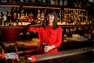 young beautiful woman prepares cocktail at bar counter