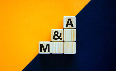 Mergers and acquisitions symbol. Concept word 'M and A - mergers and acquisitions' on wooden cubes...