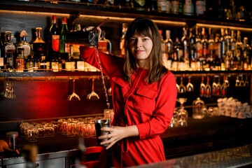 attractive woman bartender in red dress prepares cocktail