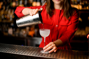 close-up of frozen glass on bar in which bartender pours drink from steel glass