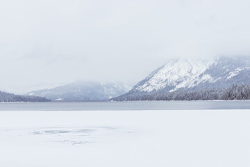 Frozen Mountain Lake Covered in Snow on Cloudy Day in Winter