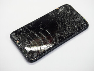 Photo of black smartphone with broken damaged display. Modern smartphone with damaged glass screen close-up isolated on white background. Device needs repair.