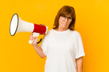 Middle age caucasian woman holding a megaphone confused, feels doubtful and unsure.