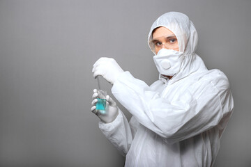 Covid19 vaccine in doctors hands. Doctor in protective medical suit, biological hazard, medical mask gloves on gray background. Coronavirus vaccine Copy space