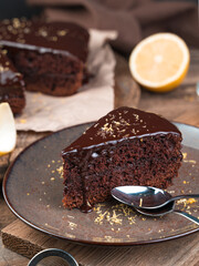 Delicious slice of chocolate cake on a brown wooden background. Side view, vertical orientation. The concept of cooking.