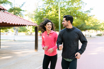 Smiling couple running in the park track