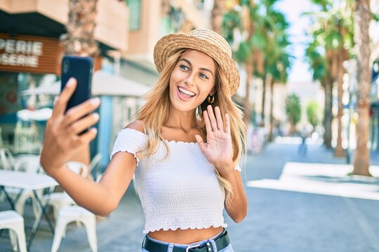 Young blonde tourist girl smiling happy doing video call using smartphone at the city.