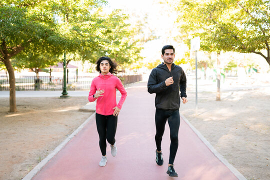 Hispanic Couple Looking Ahead And Running In The Park