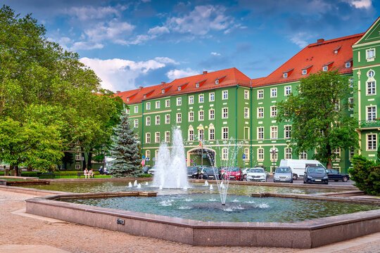 Green Buildings Of Szczecin City Council With Red Rooftops. Fountains In A Pond And Green Trees On Jasne Blonia Square, Stettin, Poland