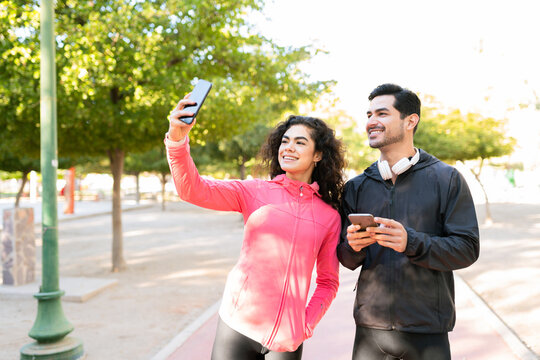 Girlfriend is taking a selfie with her boyrfriend in the park before working out