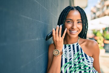 Young african american woman smiling happy listening audio message using smartphone at the city.