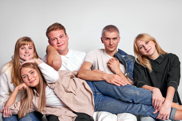 Fototapeta premium portrait of attractive stylish young people in studio floor isolated on white background, friendly people in casual wear sit posing together