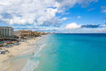 Espectacular vista aérea de la zona hotelera de Cancún con el característico mar color azul turquesa y cielo azul y nublado como fondo.