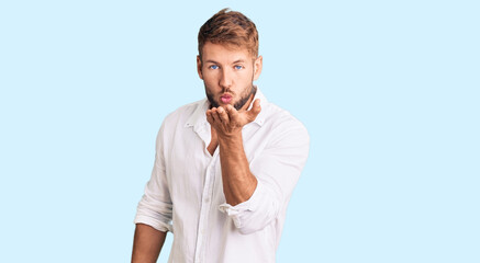 Fototapeta na wymiar Young caucasian man wearing casual clothes looking at the camera blowing a kiss with hand on air being lovely and sexy. love expression.