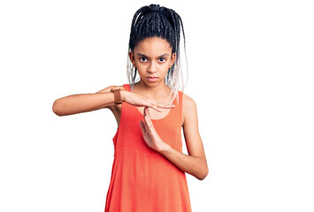 Cute african american girl wearing casual clothes doing time out gesture with hands, frustrated and...