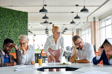 team of sad frustrated employees receiving rebuke by shouting female executive, workers are...