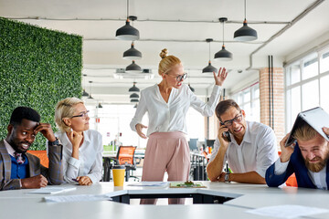 rude angry female boss executive is dissatisfied irritated by employees, scream at them, incompetent workers. in modern office