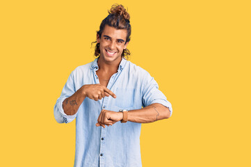 Young hispanic man wearing summer style in hurry pointing to watch time, impatience, upset and...
