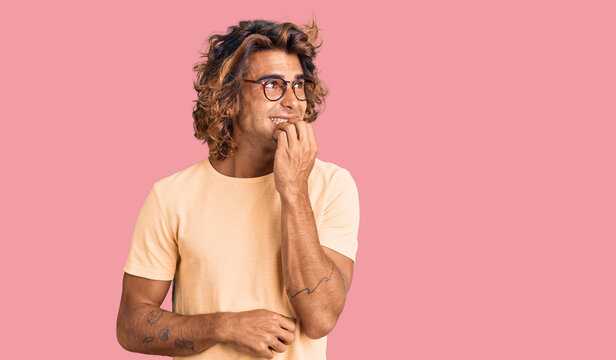 Young hispanic man wearing casual clothes and glasses looking stressed and nervous with hands on mouth biting nails. anxiety problem.