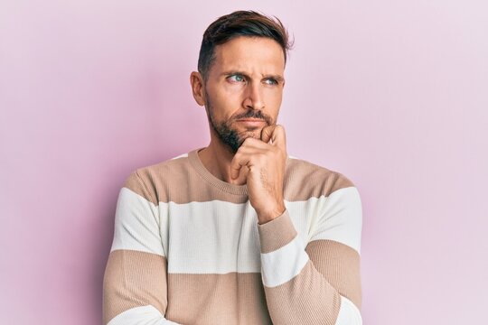 Handsome man with beard wearing casual clothes thinking concentrated about doubt with finger on chin and looking up wondering