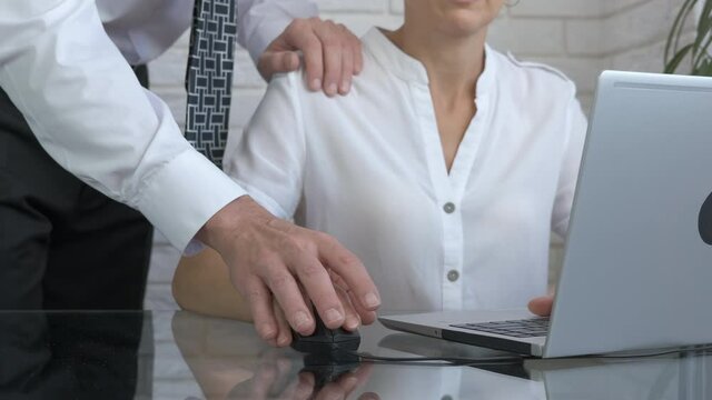 Flirt on workplace. A businessmen flirt with a woman in the office and help her with computer.