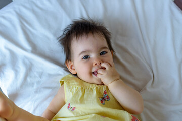 Bebe pequeño en cuna blanca con vestido amarillo