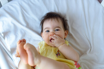 Bebe pequeño en cuna blanca con vestido amarillo