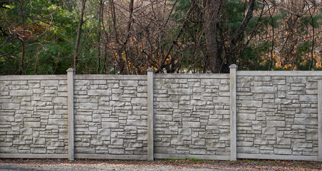Modern pattern of light stone fence wall with posts in front