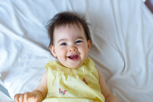 Bebe peque&ntilde;o en cuna blanca con vestido amarillo