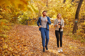 happy couple enjoying jogging on a country road through the beautiful autumn forest, exercise and fitness concept
