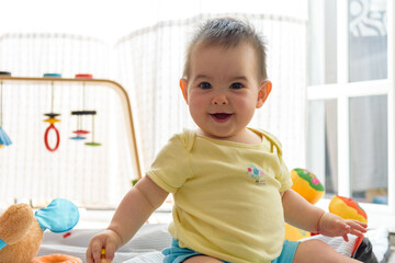 Bebe pequeño con juguetes en casa con vestido amarillo