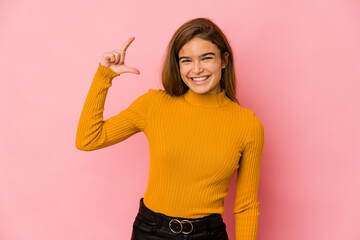 Young skinny caucasian teenager girl holding something little with forefingers, smiling and confident.