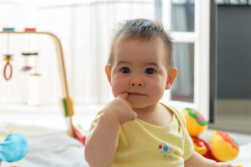 Bebe pequeño con juguetes en casa con vestido amarillo