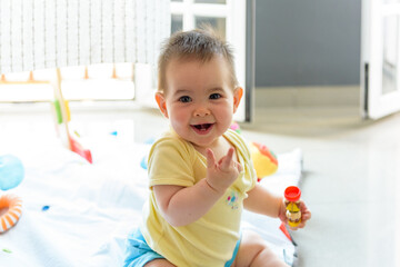 Bebe pequeño con juguetes en casa con vestido amarillo