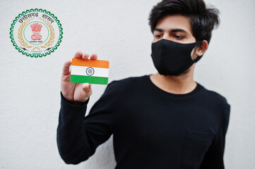 Indian man wear all black and face mask, hold India flag in hand isolated on white background with Chhattisgarh state emblem . Coronavirus India states and union territories concept. - obrazy, fototapety, plakaty