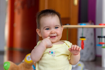 Bebe pequeño con juguetes en casa con vestido amarillo