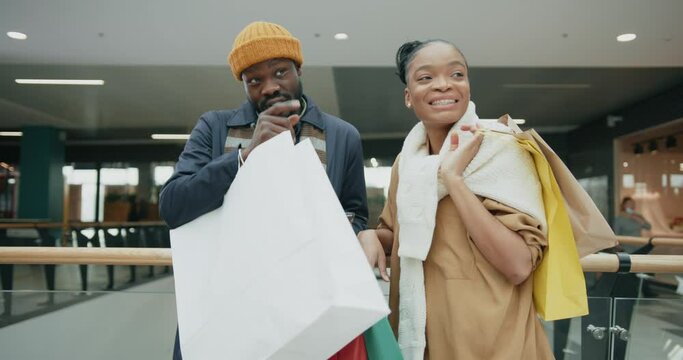 Fashionable stylish couple of afro-american man and woman communicating using smartphone while shopping for presents during holiday season sale.